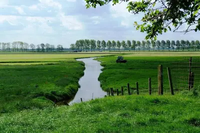 a river in a field next to a fence at Mariahoeve-Logies #'t Hooihuis in Woubrugge