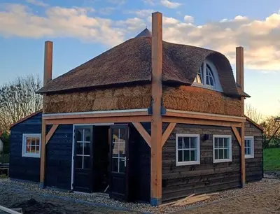 a log cabin with a thatched roof at Mariahoeve-Logies #'t Hooihuis in Woubrugge