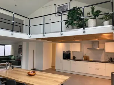 a kitchen with white cabinets and a wooden table at Luxe vakantiehuis met sauna De Barn Bergen in Bergen