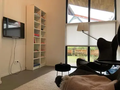 a living room with a tv and a chair at Luxe vakantiehuis met sauna De Barn Bergen in Bergen