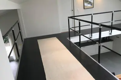 a staircase with black railings and a rug on the floor at Luxe vakantiehuis met sauna De Barn Bergen in Bergen