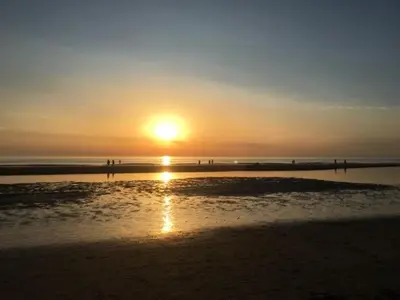a sunset on a beach with the sun setting at Luxe vakantiehuis met sauna De Barn Bergen in Bergen