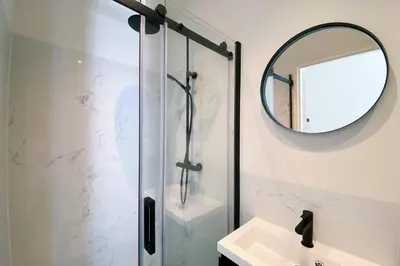 a bathroom with a shower with a mirror and a sink at Luxurious historical Loft close to the beach!! in Wassenaar