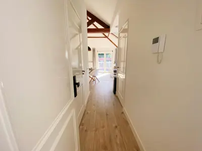 a hallway with white walls and wooden floors at Luxurious historical Loft close to the beach!! in Wassenaar