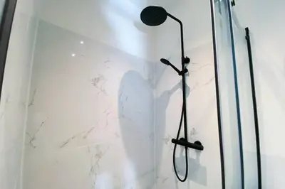 a shower in a white bathroom with a glass wall at Luxurious historical Loft close to the beach!! in Wassenaar