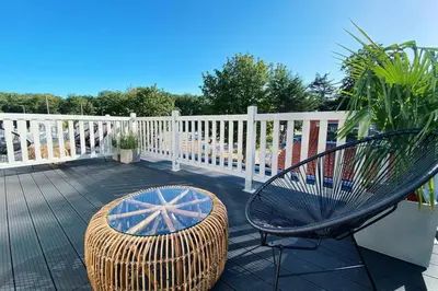 a wicker chair and a bench on a deck at Luxurious historical Loft close to the beach!! in Wassenaar