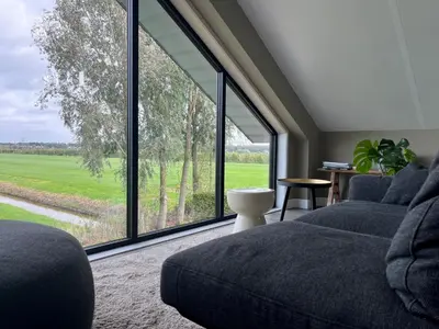 a living room with a couch and a large window at @TheLodge in Haarzuilens