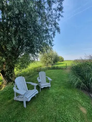 two white chairs sitting in the grass under a tree at @TheLodge in Haarzuilens