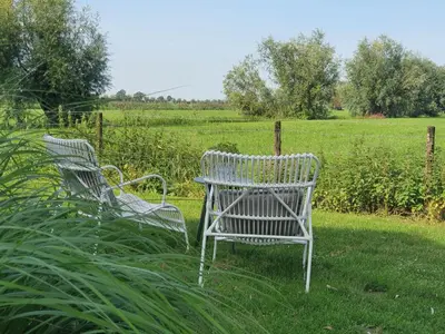 two white chairs and a table in a field at @TheLodge in Haarzuilens