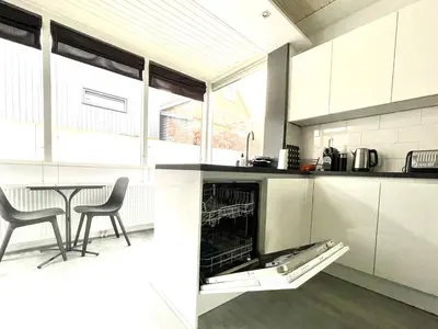 a kitchen with white cabinets and a table and chairs at Alibi aan Zee in Wijk aan Zee