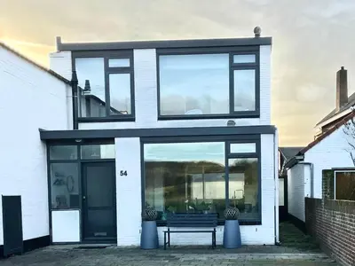 a house with large glass windows and a bench at Alibi aan Zee in Wijk aan Zee