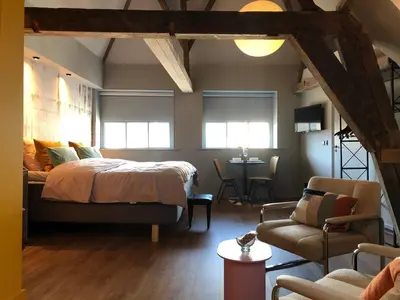 a bedroom with a bed and a chair and a table at Daen’s Greenhouse in Utrecht