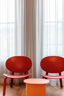 two red chairs and a table in front of a window at Daen’s Greenhouse in Utrecht