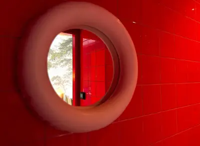 a mirror in a red bathroom with a red wall at Daen’s Greenhouse in Utrecht
