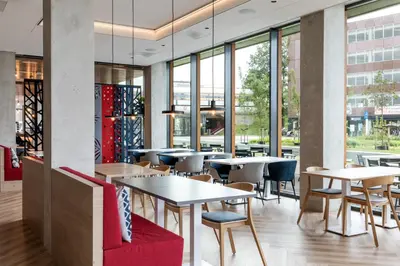 a restaurant with tables and chairs and windows at Holiday Inn Express - Almere by IHG in Almere