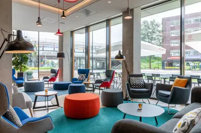 a lobby with chairs and tables and windows at Holiday Inn Express - Almere by IHG in Almere