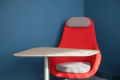 a red chair sitting next to a desk with a table at Holiday Inn Express - Almere by IHG in Almere