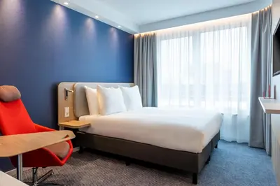 a hotel room with a bed and a red chair at Holiday Inn Express - Almere by IHG in Almere