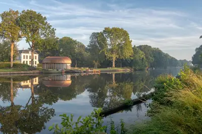 a view of a lake with a building next to it at Hotel Flora Batava in Breukelen