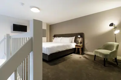 a bedroom with a bed and a chair and a tv at Hotel Flora Batava in Breukelen