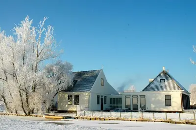 a white house with a gray roof in the snow at Amsterdam Farmland in Amsterdam
