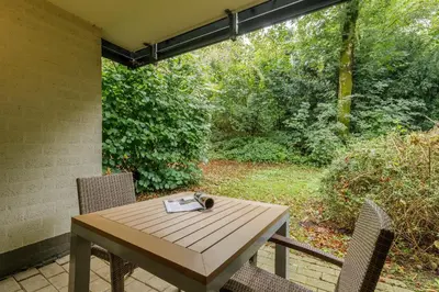a wooden table and chairs on a patio at Hotel Eemhof by Center Parcs in Zeewolde