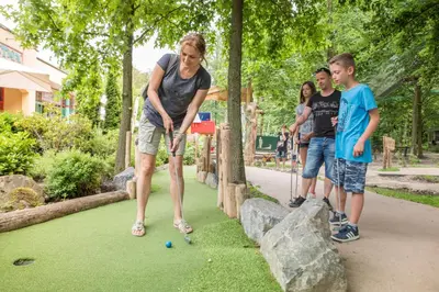 a woman playing a game of miniature golf in a park at Hotel Eemhof by Center Parcs in Zeewolde