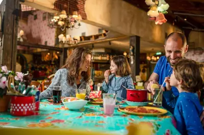 a family sitting at a table eating pizza at Hotel Eemhof by Center Parcs in Zeewolde