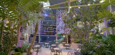 a room filled with tables and chairs and trees at Hotel Eemhof by Center Parcs in Zeewolde