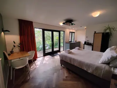 a bedroom with a bed and a desk and a table at Kwadijkerbos in Kwadijk