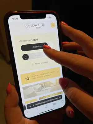 a person holding a cell phone with a website on it at Hotel Lowietje Lisse - Keukenhof - Free Parking in Lisse