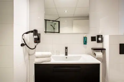 a white bathroom with a sink and a mirror at Hotel Lowietje Lisse - Keukenhof - Free Parking in Lisse