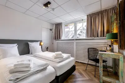 a hotel room with two beds and a desk at Broeck Oudewater in Oudewater