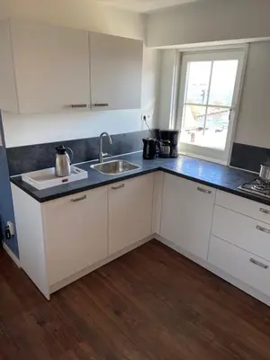 a kitchen with white cabinets and a sink and a window at Appartement Aqua in Oude Wetering