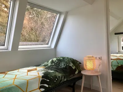 a bedroom with a bed and two windows at Das Luxus Dünenhäuschen mit Wellnesszugang in Egmond aan Zee