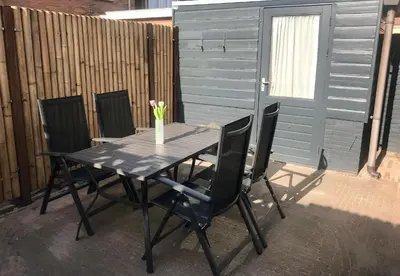 a black table with chairs and a vase with flowers on it at Das Luxus Dünenhäuschen mit Wellnesszugang in Egmond aan Zee