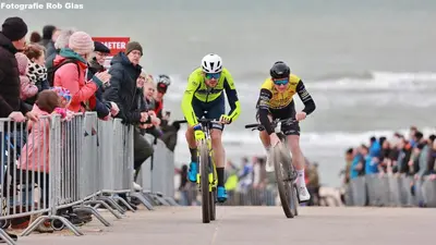 two people riding bikes on the beach with a crowd at Das Luxus Dünenhäuschen mit Wellnesszugang in Egmond aan Zee