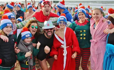 a group of people dressed in santa hats on the beach at Das Luxus Dünenhäuschen mit Wellnesszugang in Egmond aan Zee