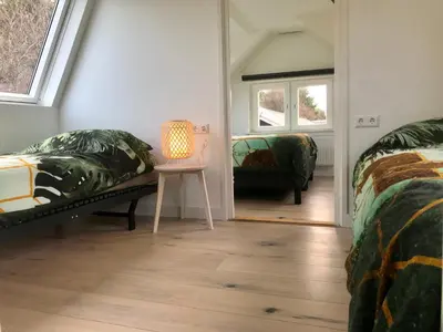 a bedroom with two beds and a table with a lamp at Das Luxus Dünenhäuschen mit Wellnesszugang in Egmond aan Zee