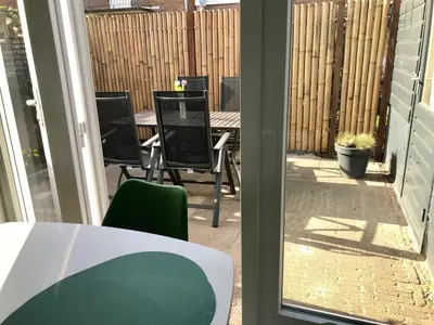 an outside view of a patio with a table and chairs at Das Luxus Dünenhäuschen mit Wellnesszugang in Egmond aan Zee