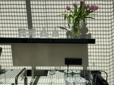 a vase of purple flowers on a shelf with glasses at vondice hotel in Amsterdam