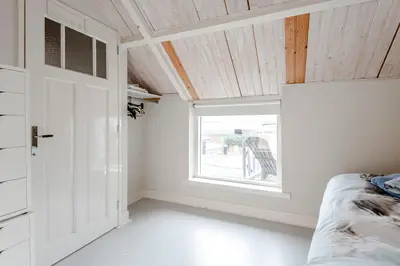 a bedroom with a window and a bed and a door at Kusthuiskatwijk in Katwijk aan Zee