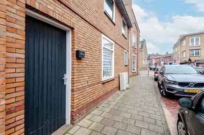 a brick building with a black door on a street at Kusthuiskatwijk in Katwijk aan Zee