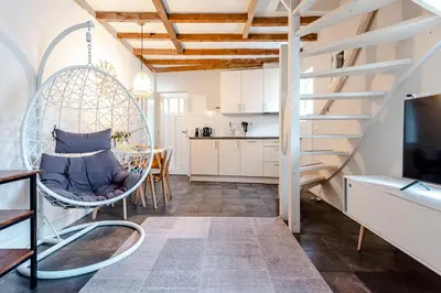 a living room with a swing chair and a kitchen at Kusthuiskatwijk in Katwijk aan Zee