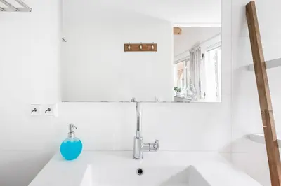 a white bathroom with a sink and a blue vase at Woubrugge Logies in Woubrugge