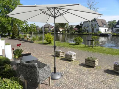 a white umbrella sitting next to a table and chairs at Woubrugge Logies in Woubrugge