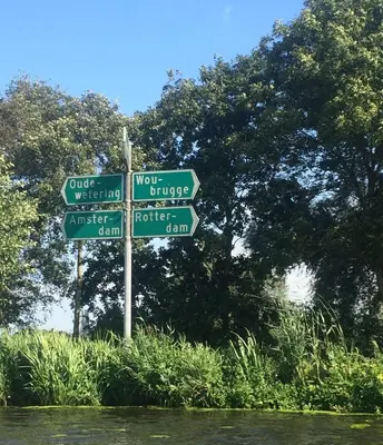 a pole with street signs in front of a river at Woubrugge Logies in Woubrugge