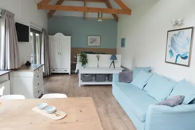 a living room with a blue couch and a table at Woubrugge Logies in Woubrugge
