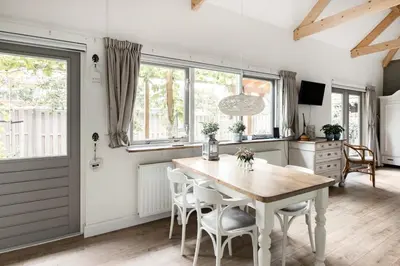 a kitchen with a table and chairs and windows at Woubrugge Logies in Woubrugge