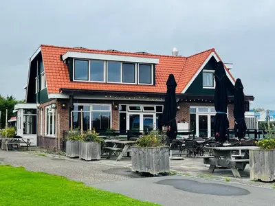 a building with tables and umbrellas in front of it at Millsight in Uitgeest